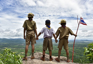 Boy Scouts Looking Out Over a Cliff Holding a Flag