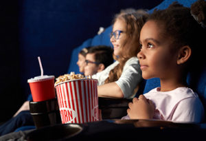 Children Watching Screen in Movie Theater While Eating Popcorn
